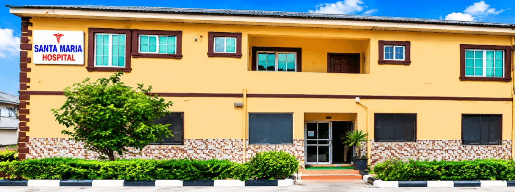 Exterior view of the two-story Santa Maria Hospital building with yellow facade, brown trim, and signage under a blue sky